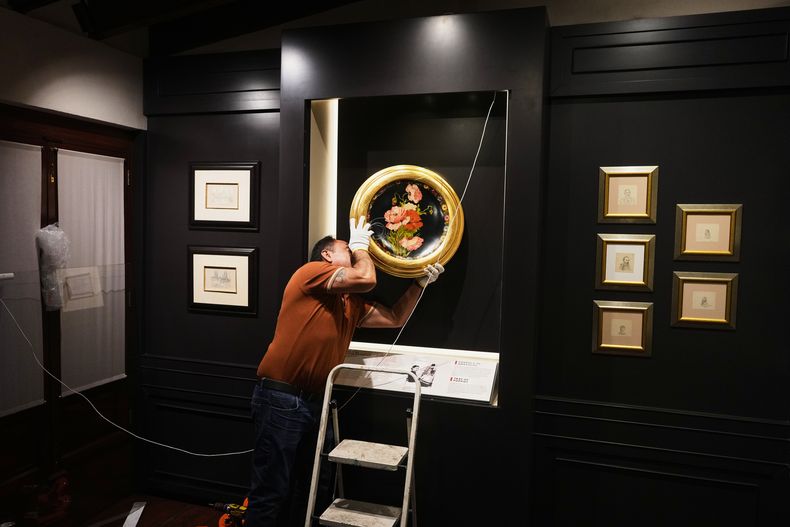 Un trabajador cuelga Una bandeja de amapolas, una de las primeras obras de Frida Kahlo que pintó como regalo para su tía Ana, en preparación para la apertura del nuevo Museo Casa Kahlo, una casa comprada por el padre de Kahlo después de darle la icónica Casa Azul a su hija como regalo de bodas, en la Ciudad de México, el miércoles 10 de septiembre de 2025. (Foto AP/Eduardo Verdugo)