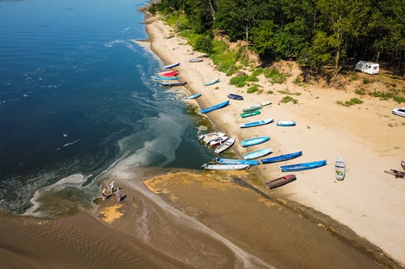 Varias personas se paran en un banco de arena en el río Danubio, normalmente cubierto de agua, que quedó expuesto debido al nivel extremadamente bajo del agua tras una prolongada sequía, en Corabia, Rumanía, el 29 de julio de 2026. (AP Foto/Nicolae Dumitrache)