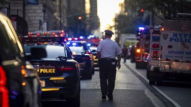 Un policía camina entre vehículos policiales en la calle 52, frente a un edificio de oficinas de Manhattan en el que hubo un tiroteo, el lunes 28 de julio de 2025, en Nueva York. (AP Foto/Angelina Katsanis)