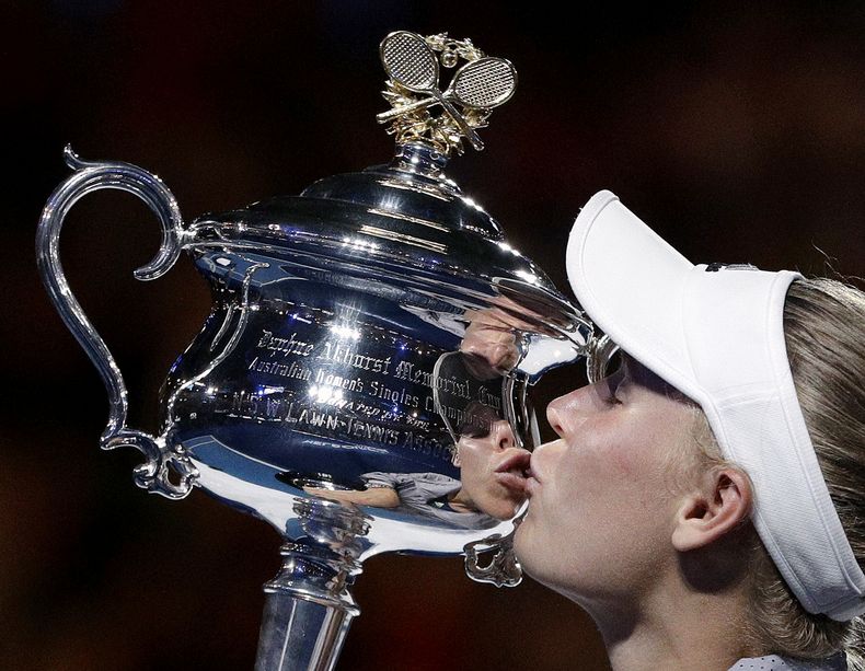 ARCHIVO - Caroline Wozniacki besa el trofeo de campeona del Abierto de Australia tras derrotar a Simona Halep en la final, el sábado 27 de enero de 2018. (AP Foto/Dita Alangkara)
