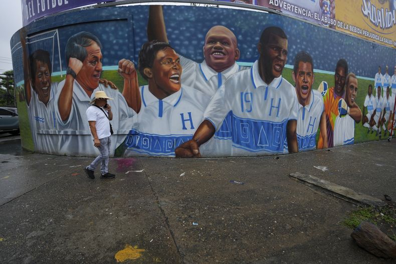 Un hombre camina por un mural de leyendas del fútbol hondureño afuera del estadio Francisco Morazán previo al partido entre Honduras y México, en San Pedro Sula, Honduras, el jueves 14 de noviembre de 2024. (AP Foto/Moisés Castillo)