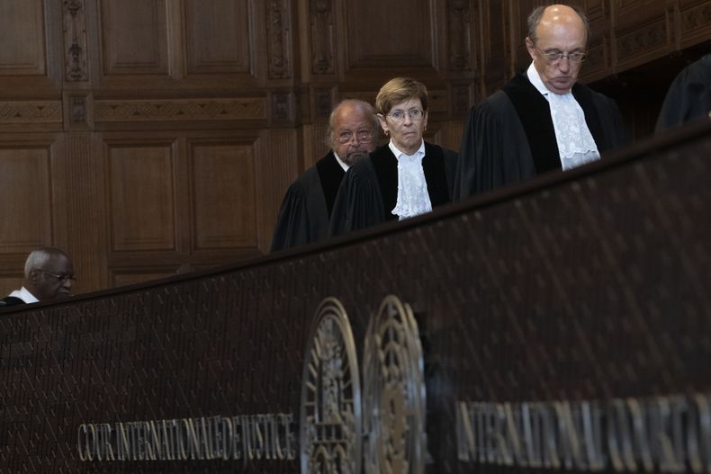 La jueza presidenta, Joan Donoghue (centro), entra en una sala de la Corte Internacional de Justicia acompañada por el juez Peter Tomka (derecha) y el juez Ronny Abraham (izquierda), para una sesión de la batalla legal de Ucrania contra Rusia por las acusaciones de genocidio utilizadas por Moscú para justificar su invasión del país, en La Haya, Holanda, el 19 de septiembre de 2023. (AP Foto/Peter Dejong)