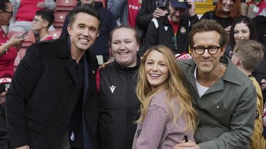 Los codueños de Wrexham Ryan Reynolds (derecha), su esposa Blake Lively (segunda derecha) y Rob McElhenney (izquierda) posan con hinchas previo al partido contra Charlton Athletic, el sábado 26 de abril de 2025, en Wrexham, Gales. (AP Foto/Jon Super)