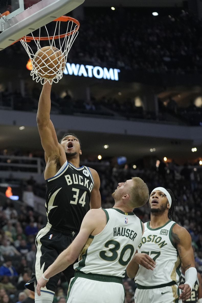 Giannis Antetokounmpo, de los Bucks de Milwaukee, clava el balón sobre Sam Hauser, de los Celtics de Boston, durante la segunda mitad del partido de baloncesto de la NBA, el jueves 11 de enero de 2024, en Milwaukee. (AP Foto/Morry Gash)