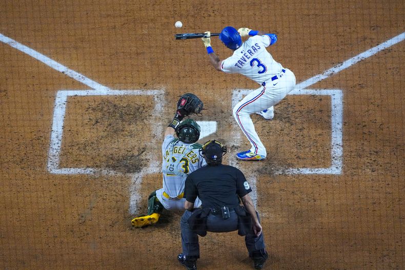 Leody Taveras (3) de los Rangers de Texas deja caer un toque de sacrificio frente al receptor de los Atléticos de Oakland, Shea Langeliers (23), y el umpire del plato, James Hoye, durante la tercera entrada de un juego de béisbol el miércoles 30 de abril de 2025, en Arlington, TX. (AP Foto/Julio Cortez)