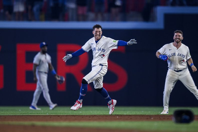 Ernie Clement (centro), de los Azulejos de Toronto, festeja su sencillo que significó la victoria sobre los Rangers de Texas, el viernes 26 de julio de 2024 (Christopher Katsarov/The Canadian Press via AP)