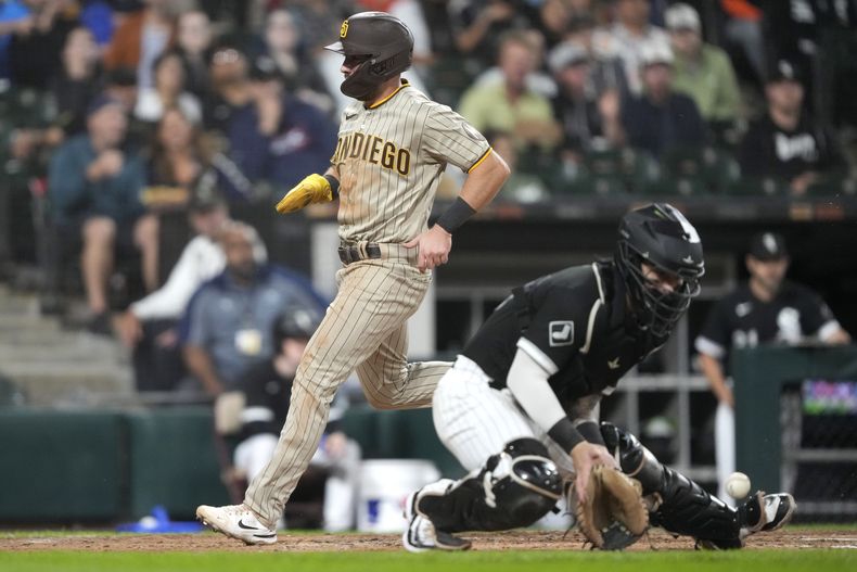 Matthew Batten, de los Padres de San Diego, anota a un costado del receptor de Medias Blancas de Chicago, Korey Lee, durante la quinta entrada del juego de béisbol del viernes 29 de septiembre de 2023, en Chicago. (AP Foto/Charles Rex Arbogast)