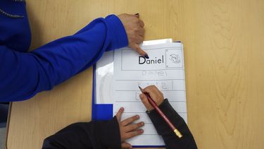 ARCHIVO - Tania Ortiz, profesora auxiliar del programa Head Start de Easterseals, ayuda a un alumno a practicar el escribir su nombre, el 29 de enero de 2025, en Miami. (AP Foto/Rebecca Blackwell, archivo)