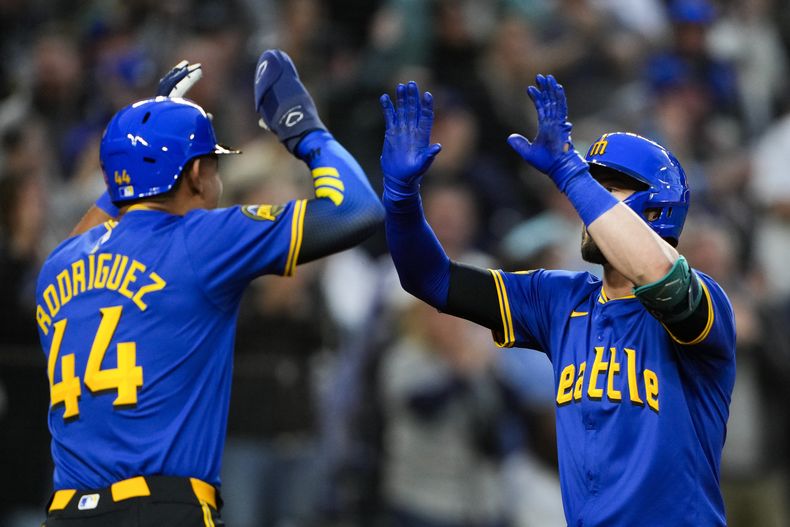 El dominicano de los Marineros de Seattle Julio Rodríguez festeja con Mitch Haniger, quien pegó un grand slam en la sexta entrada ante los Diamondbacks de Arizona el viernes 26 de abril del 2024. (AP Foto/Lindsey Wasson)