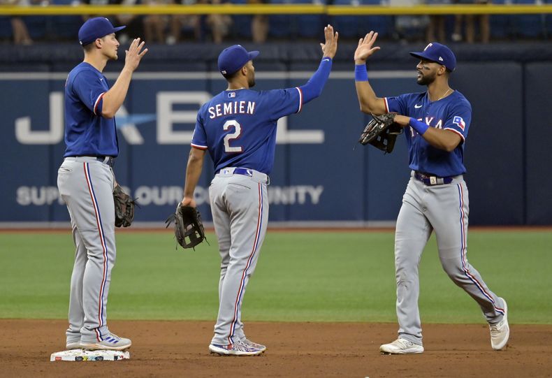 De izquierda a derecha, Corey Seager, Marcus Semien y el dominicano Leody Taveras, festejan la victoria de los Rangers de Texas sobre los RAys de Tampa Bay, el sábado 10 de junio de 2023 (AP Foto/Steve Nesius)