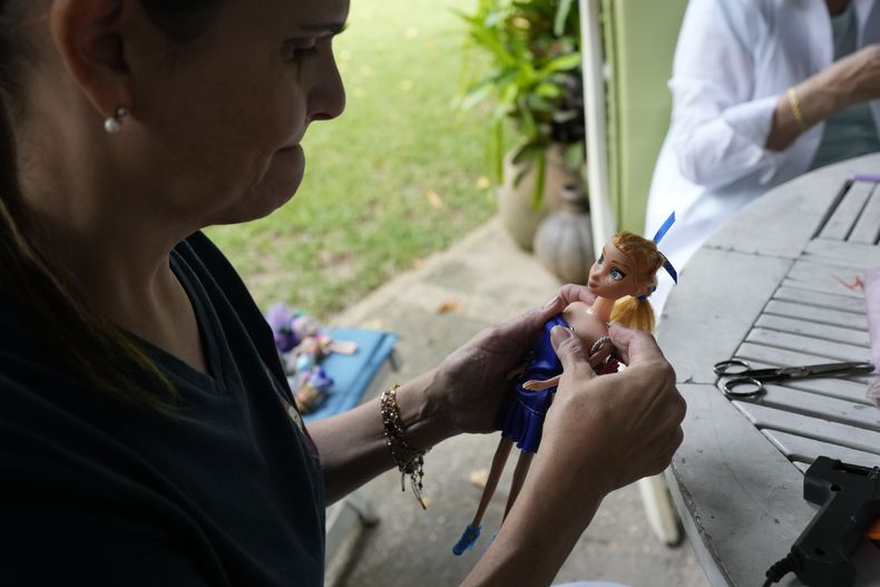 Una voluntaria viste una muñeca donada en la organización sin fines de lucro Hospital de los Peluches, en donde recuperan y reparan juguetes usados para donarlos a niños vulnerables como regalos de Navidad, en Caracas, Venezuela, el jueves 5 de diciembre de 2024. (AP Foto/Ariana Cubillos)