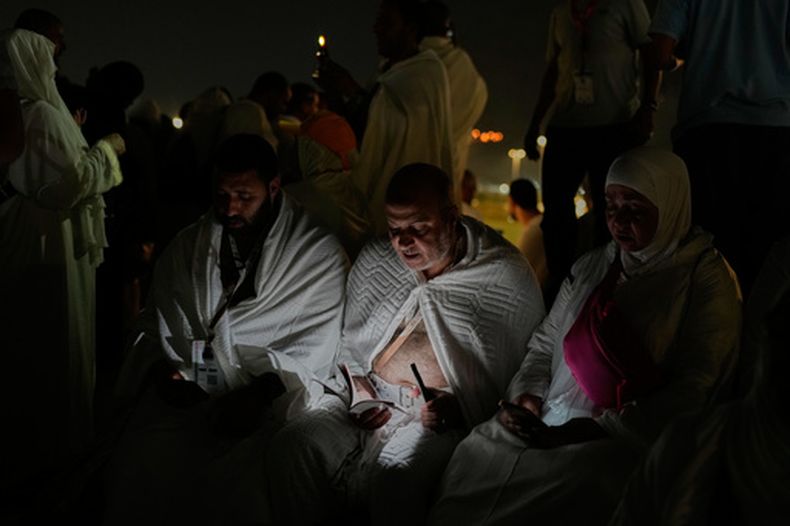 Peregrinos musulmanes leen una copia del libro sagrado islámico, el Corán, sobre una colina rocosa conocida como la montaña de la Misericordia, en la llanura de Arafat, durante el peregrinaje anual del haj cerca de la ciudad sagrada de La Meca, en Arabia Saudí, el martes 26 de mayo de 2026. (AP Foto/Altaf Qadri)