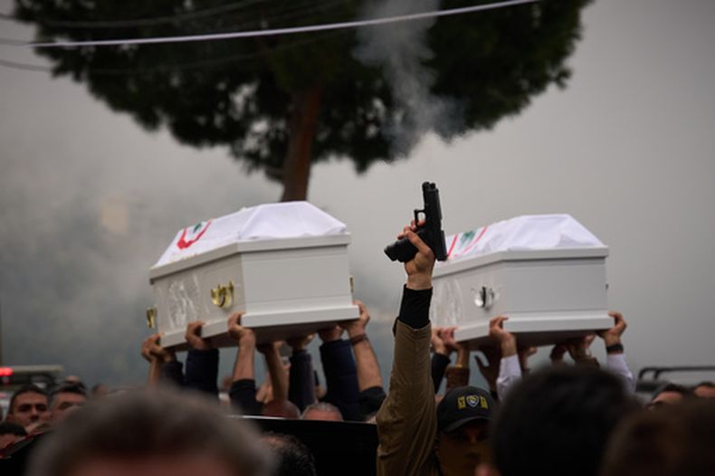 Una persona dispara una pistola mientras otros llevan los féretros de Pierre Mouawad, del partido Fuerzas Libanesas, y su esposa, en el funeral en Yahshush, Líbano, el 7 de abril del 2026. (AP foto/Emilio Morenatt