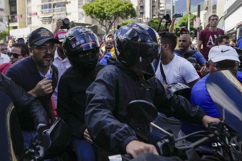 La líder de la oposición María Corina Machado, con un casco, sentada en la parte trasera de una motocicleta mientras se la llevan después de dirigirse a la gente en una protesta contra el presidente Nicolás Maduro en Caracas, Venezuela, el jueves 9 de enero de 2025, el día antes de su toma de posesión para un tercer mandato. (AP Foto/Matías Delacroix)