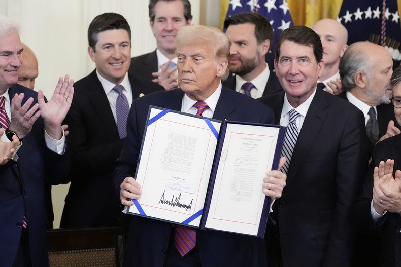 El presidente estadounidense Donald Trump muestra la Ley GENIUS, que regula las stablecoins, un tipo de criptomoneda, tras firmarla en la Sala Este de la Casa Blanca, el viernes 18 de julio de 2025, en Washington. (AP Foto/Alex Brandon)