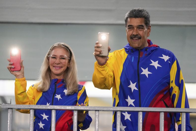 El presidente Nicolás Maduro y la primera dama Cilia Flores encienden las lámparas de sus teléfonos móviles después de votar en las elecciones presidenciales en Caracas, Venezuela, el domingo 28 de julio de 2024. (AP Foto/Fernando Vergara)