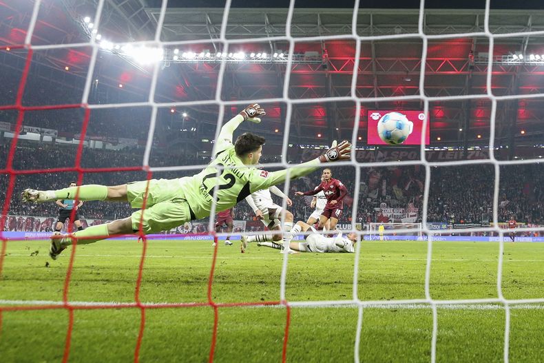 Xavi Simons (centro) de Leipzig remata ante el arquero Nikola Vasilj de St. Pauli durante un partido de la Bundesliga, el domingo 9 de febrero de 2025. (Jan Woitas/dpa vía AP)