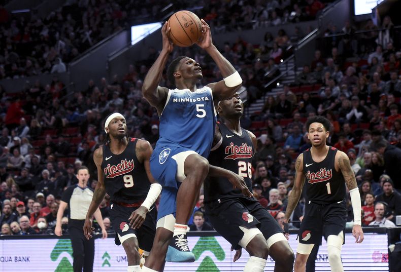 Anthony Edwards, base de los Timberwolves de Minnesota, salta hacia el canasto frente a Jerami Grant (9) y Duop Reath (26), de los Trail Blazers de Portland, el jueves 15 de febrero de 2024 (AP Foto/Steve Dykes)