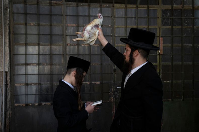 ARCHIVO - Un judío ultraortodoxo sacude un pollo sobre la cabeza de su hijo en Bnei Brak, Israel, el jueves 10 de octubre de 2024, como parte del ritual de Kaparot un día antes de la festividad judía de Yom Kippur. (AP Foto/Oded Balilty, Archivo)