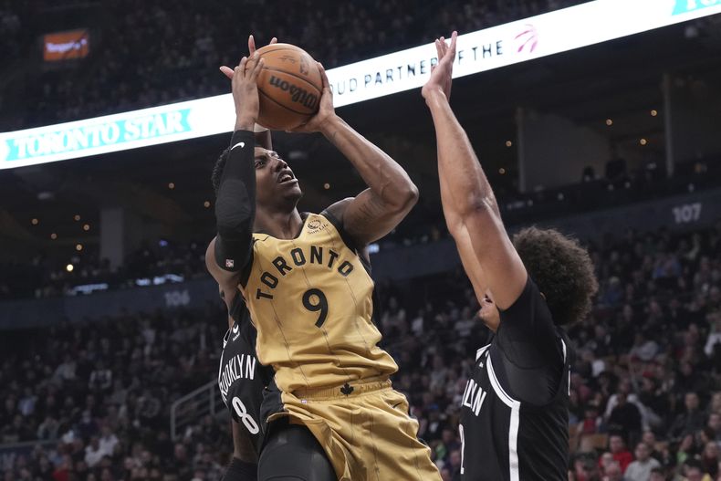 RJ Barrett, de los Raptors de Toronto, dispara frente a Cameron Johnson, de los Nets de Brooklyn, en el partido del jueves 22 de febrero de 2024 (Chris Young/The Canadian Press via AP)