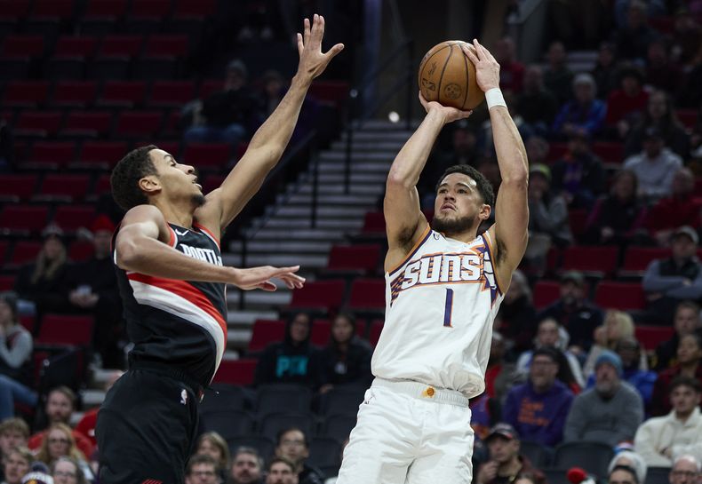 Devin Booker, derecha, de los Suns de Phoenix, se prepara a disparar sobre la marca de Kris Murray, de los Trail Blazers de Portland, durante la primera mitad del juego de baloncesto de la NBA, en Portland, Oregon, el domingo 14 de enero de 2024. (AP Foto/Craig Mitchelldyer)