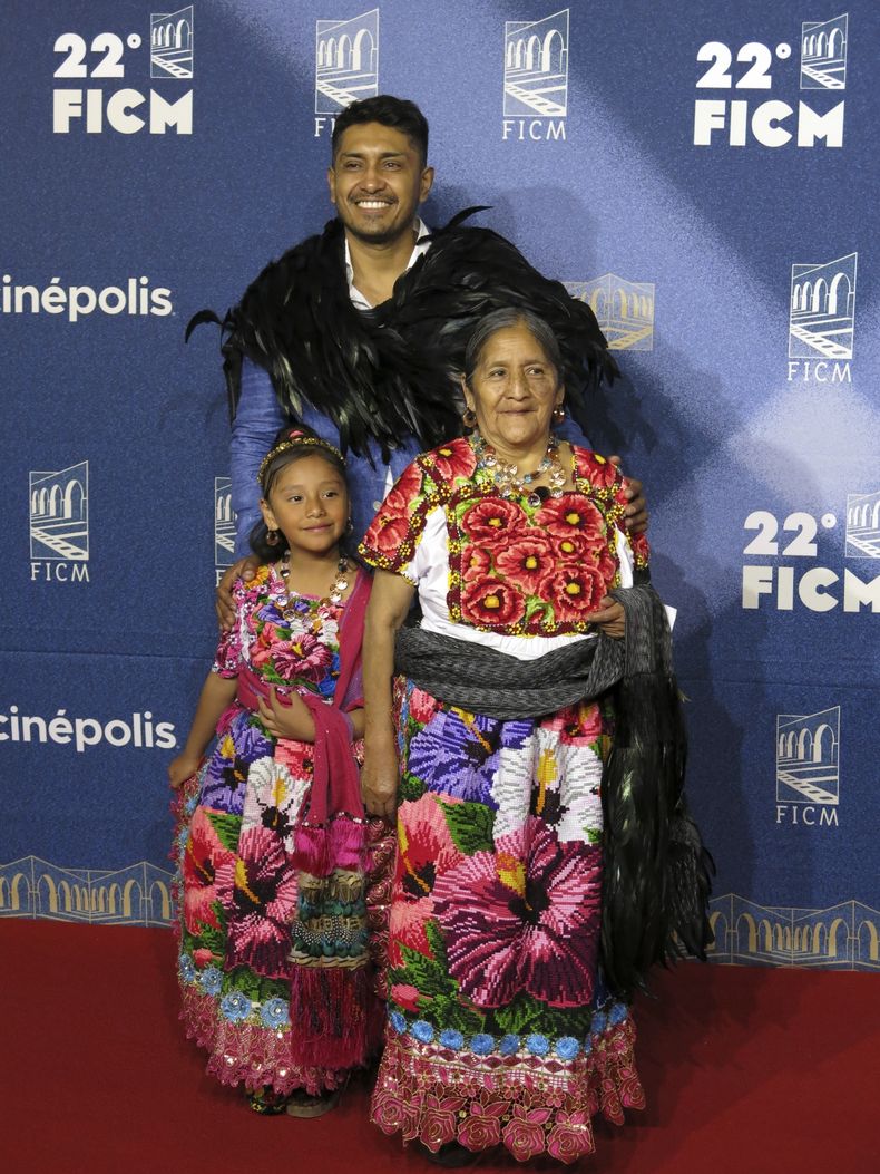 El actor Tenoch Huerta, fondo, llega a la alfombra roja de la película Pedro Páramo con la artesana purépecha Feliciana Bautista, derecha, y Leslie Bautista en el Festival Internacional de Cine de Morelia, el sábado 19 de octubre de 2024, en Morelia, México. (Foto AP/Berenice Bautista)