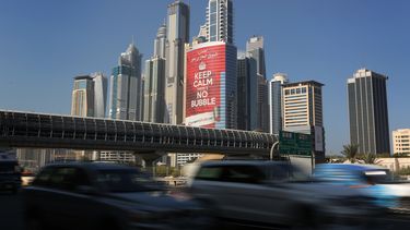 americateve | En esta foto del mi&eacute;rcoles 13 de noviembre de 2013, veh&iacute;culos pasan junto a una torre con un cartel que afirma "tranquilos, no hay burbuja", en el distrito Marina de Dubai, Emiratos Arabes Unidos. Dubai ser&aacute; anfitriona de la