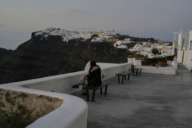 Una turista se sienta en Firostefani mientras las autoridades griegas toman medidas de emergencia en respuesta a la actividad sísmica en la popular isla turística griega de Santorini, en el mar Egeo, el lunes 3 de febrero de 2025. (AP Foto/Petros Giannakouris)