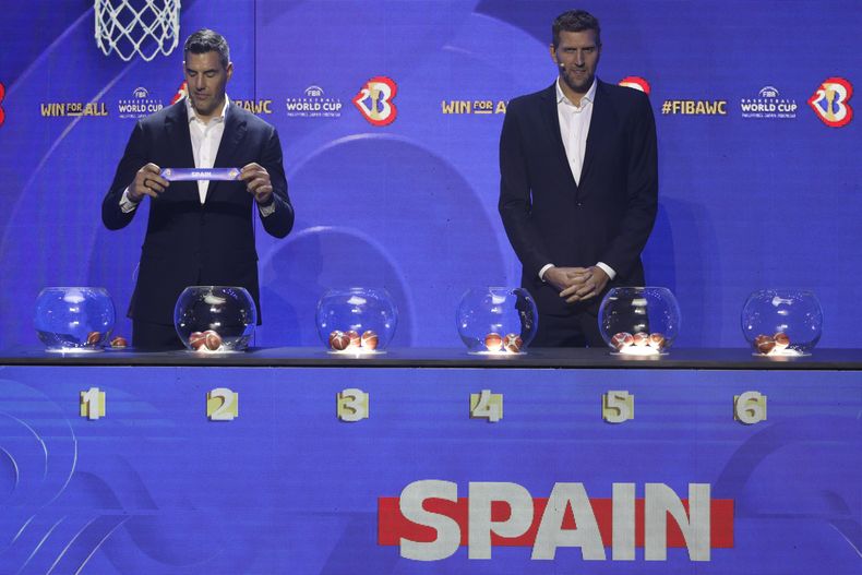 El embajador de FIBA y exestrella de la NBA Luis Scola muestra el papel con el nombre de España junto al exbasketbolsita alemán Dirk Nowitzki durante el sorteo al Mundial de Baloncesto en Quezon, Filipinas el sábado 29 de abril del 2023. (AP Foto/Josefino de Guzman)