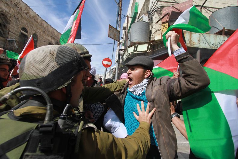 Palestinos chocan con soldados israel&iacute;es durante una manifestaci&oacute;n contra el cierre de la principal calle c&eacute;ntrica de Hebr&oacute;n, Cisjordania, viernes 21 de febrero de 2014. (AP Foto/Nasser Shiyoukhi)