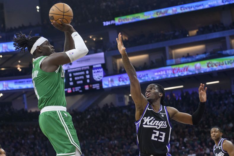 Jrue Holiday, base de los Celtics de Boston, dispara frente a Keon Ellis, base de los Kings de Sacramento, en el partido del miércoles 20 de diciembre de 2023 (AP Foto/Randall Benton)