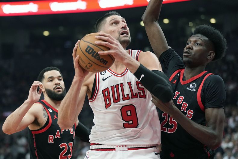 ARCHIVO - Nikola Vucevic (9), pívot de los Bulls de Chicago, busca encestar con la presión defensiva de Chris Boucher (25), de los Raptors de Toronto y Fred VanVleet (23), durante la primera mitad del juego de baloncesto de la NBA, en el torneo play-in, el miércoles 12 de abril de 2023, en Toronto. Los Bulls y Nikola Vucevic acordaron el miércoles 28 de junio de 2023 a una extensión de contrato de tres años y 60 millones de dólares. (Frank Gunn/The Canadian Press via AP, Archivo)
