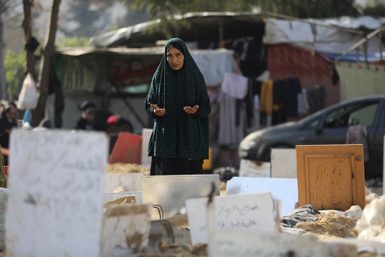 Palestinos visitan las tumbas de los fallecidos en los bombardeos israelíes sobre la Franja de Gaza, sepultados en el interior de los terrenos del hospital de Shifa, en la Ciudad de Gaza, el 31 de diciembre de 2023. (AP Foto/Mohammed Hajjar)