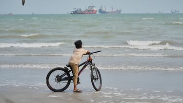 ARCHIVO - Una gaviota sobrevuela a un niño en bicicleta en una playa frente a buques comerciales anclados en el estrecho de Ormuz, en Bandar Abbas, Irán, el 7 de septiembre de 2026. (AP Foto/Vahid Salemi, archivo)