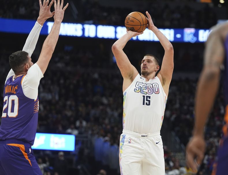 El pívot de los Nuggets de Denver, Nikola Jokic, a la derecha, sube a canasta mientras el pívot de los Suns de Phoenix, Jusuf Nurkic, defiende en la primera mitad de un partido de baloncesto de la NBA, el lunes 23 de diciembre de 2024, en Denver. (AP Foto/David Zalubowski)