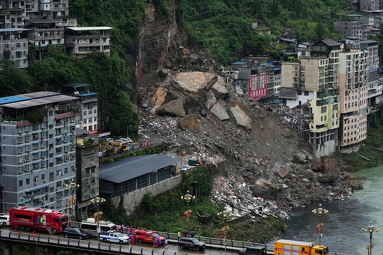 Rescatistas esperan en un puente mientras se preparan para llevar a cabo una operación de búsqueda y rescate en el lugar donde se produjo un deslave, en el condado de Pengshui, en la provincia suroccidental de Chongqing, Chija, el 18 de julio de 2026. (AP Foto/Andy Wong)