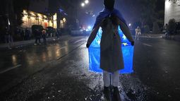 Una mujer sostiene una bandera de la Unión Europea en una protesta contra la decisión del gobierno de suspender las negociaciones para unirse al bloque, en Tiflis, Georgia, la madrugada del sábado 7 de diciembre de 2024. (AP Foto/Pavel Bednyakov)