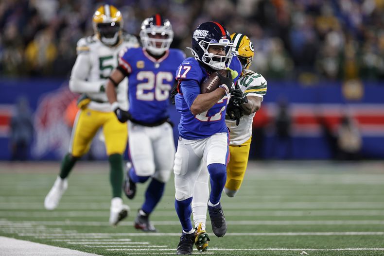 WanDale Robinson (17), wide receiver de los Giants de Nueva York, corre con el balón para dejar a su equipo en rango de gol de campo, mientras Keisean Nixon (25), cornerback de los Packers de Green Bay busca derribarlo durante el cuarto periodo del juego de la NFL del lunes 11 de diciembre de 2023, en East Rutherford, Nueva Jersey. (AP Foto/Adam Hunger)