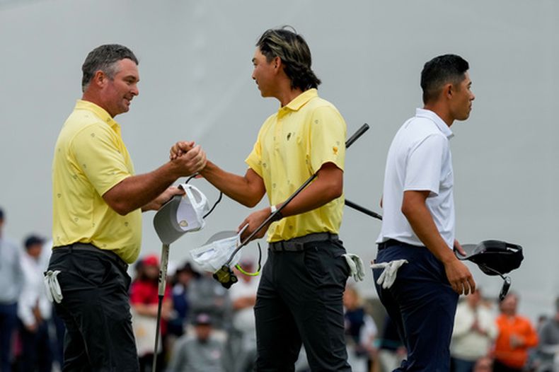 Ryan Fox, de Nueva Zelanda, izquierda, felicita a su compañero Min Woo Lee, de Australia, ambos del Equipo Internacional, mientas Collin Morikawa, de Estados Unidos, derecha, camina en el green del hoyo 18 del torneo de golf Presidents Cup, en la segunda ronda, el viernes 25 de septiembre de 2026, en el Medinah Country Club, en Medinah, Illinois. (AP Foto/Chris Carlson)