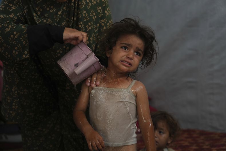 Rida Abu Hadayed, de 32 años, refresca a su hija Azhar, de dos, con agua en el interior de su tienda de campaña en un campo para desplazados en Jan Yunis, en el sur de Gaza el 1 de julio de 2025. (AP Foto/Abdel Kareem Hana)