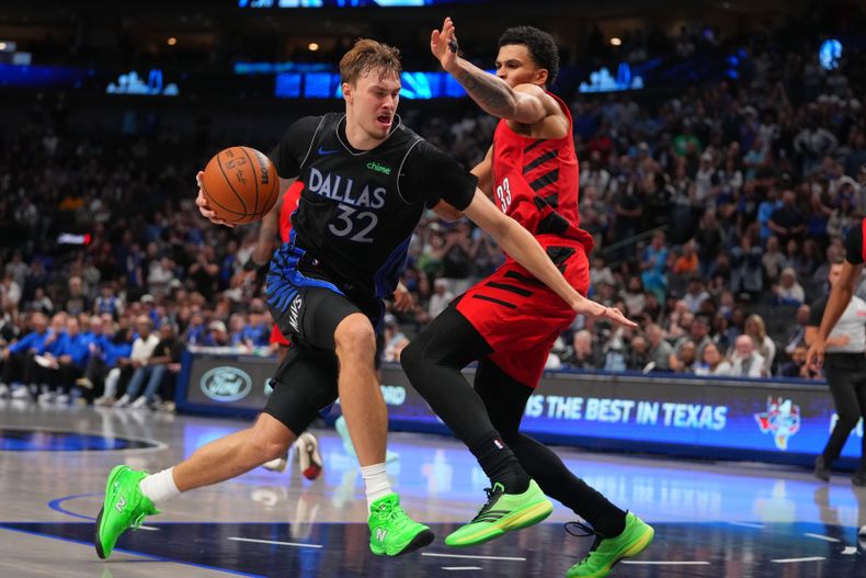 Cooper Flagg (32), de los Mavericks de Dallas, lelva el balón ante Toumani Camara (33), de los Trail Blazers de Portland, durante la segunda mitad del juego de baloncesto de la NBA, el domingo 16 de noviembre de 2025, en Dallas. (AP Foto/Julio Cortez)