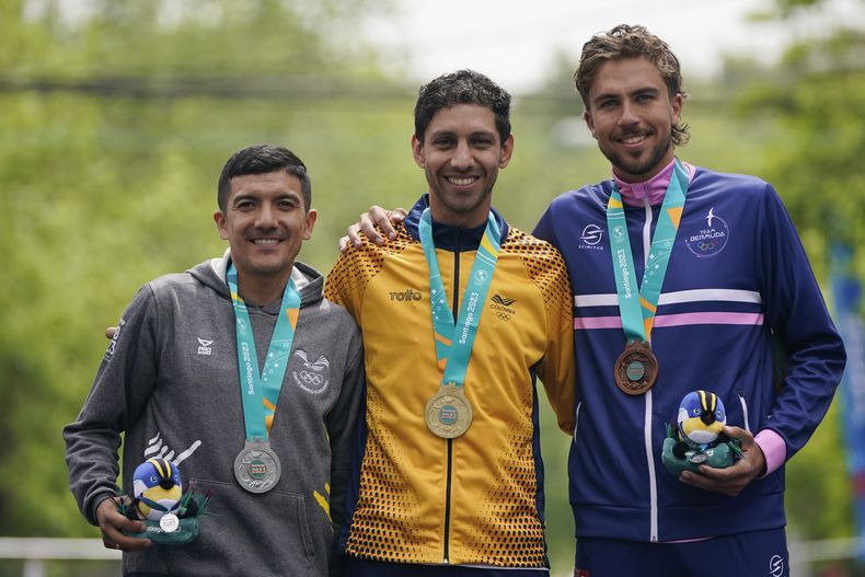 Desde la izquierda, los ciclistas Richard Carapaz, de Ecuador; Walter Vargas, de Colombia; y Conor White, de Bermuda, posan con sus medallas tras la prueba de ruta contrarreloj en los Juegos Panamericanos en Isla de Maipo, Chile, domingo 22 de Octubre, 2023. (AP Foto/Eduardo Verdugo)