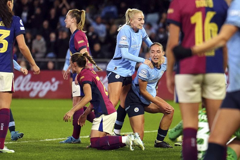 Naomi Layzell, del Manchester City, a la derecha, se arrodilla mientras celebra después de anotar el primer gol durante el partido de fútbol del grupo D de la Liga de Campeones femenina entre el Manchester City FC y el FC Barcelona en Manchester, Inglaterra, el miércoles 9 de octubre de 2024. (Martin Rickett/PA vía AP)
