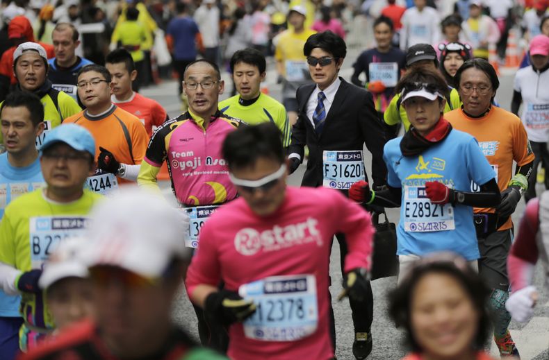 Un corredor vestido de ejecutivo, con traje, corbata y malet&iacute;n, participa en el Marat&oacute;n de Tokio, el domingo 23 de febrero de 2014. La prueba fue ganada por los africanos en ambas ramas. En la masculina se coron&oacute; el keniano Dickson Ch