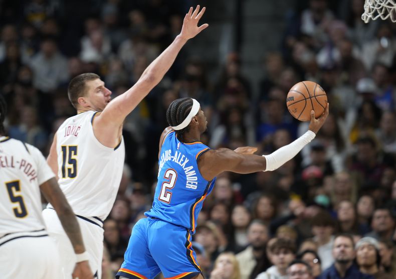 Shai Gilgeous-Alexander, del Thunder de Oklahoma City, dispara frente a Nikola Jokic, de los Nuggets de Denver, el viernes 29 de diciembre de 2023 (AP Foto/David Zalubowski)