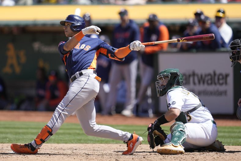El dominicano Jeremy Peña, de los Astros de Houston, conecta un doblete adelante del cátcher Shea Langeliers, de los Atléticos de Oakland, en el juego del sábado 27 de mayo de 2023 (AP Foto/Jeff Chiu)
