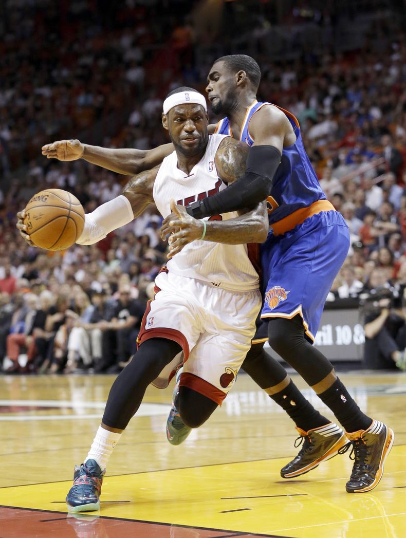 LeBron James del Heat de Miami es objeto de una falta cometida por Tim Hardaway Jr., (derecha) de los Knicks de Nueva York el domingo 6 de abril de 2014. (AP Foto/Wilfredo Lee)