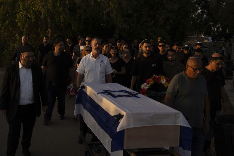 Varias personas trasladan el féretro, envuelto en la bandera israelí, de Sagiv Ben Svi, asesinado por insurgentes de Hamás en un festival de música, en un cementerio en Holon, en el centro de Israel, el 26 de octubre de 2023. (AP Foto/Petros Giannakouris)