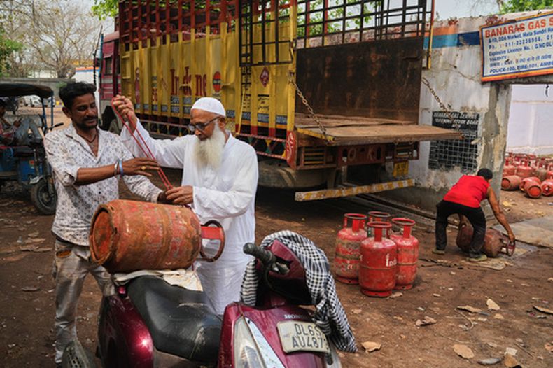 Un anciano ata un cilindro de gas a su scooter tras recogerlo de un almacén en Nueva Delhi, el jueves 19 de marzo de 2026. (AP Foto/Manish Swarup)