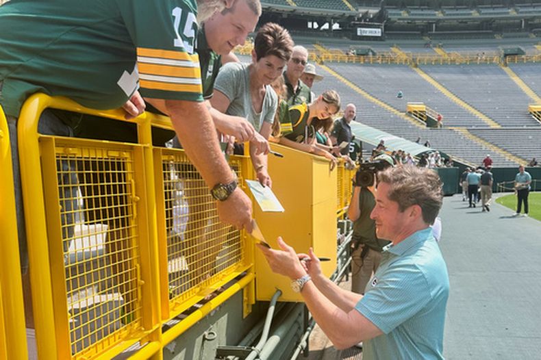 El presidente y director ejecutivo de los Packers de Green Bay Ed Policy, derecha, firma autógrafos a fanáticos después de la reunión anual de accionistas del equipo, el lunes 27 de julio de 2026, en el estadio Lambeau Field, en Green Bay, Wisconsin. (AP Foto/Steve Megargee)